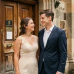 Jeune couple adulte souriant devant une mairie historique lors de leur mariage civil