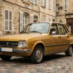 Renault 5 vintage des années 1970 garée sur un pavé français, carrosserie jaune moutarde et pare-chocs chromés, vue en trois quarts